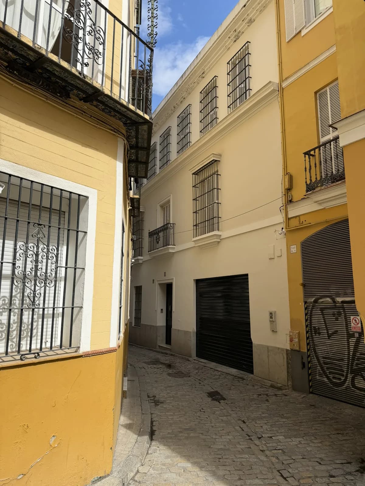 Geel-witte gevels in een smalle straat in Sevilla