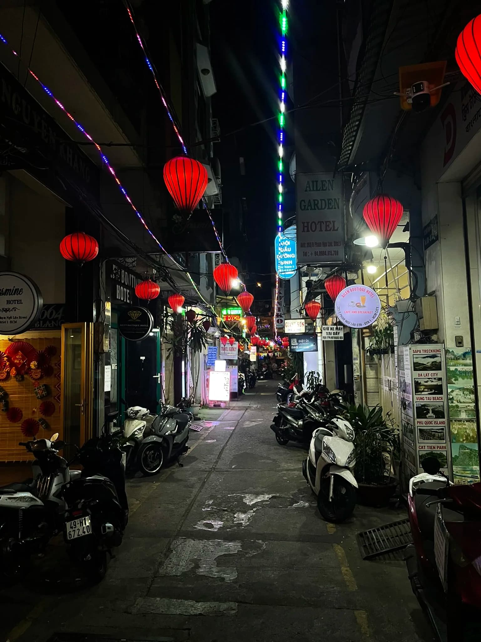 Smalle avondstraat met lampionnen en scooters in Ho Chi Minh City